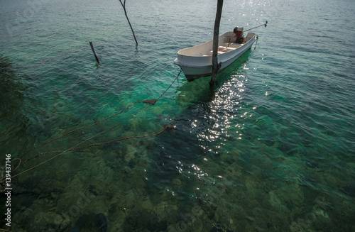 Small boat in the sea with ropes and wooden pole