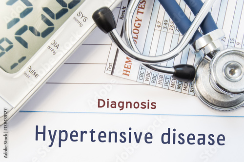 Diagnosis Hypertensive disease. Stethoscope, hematology blood test result and digital tonometer lie on sheet of paper with printed title diagnosis of vascular disease Hypertensive disease photo