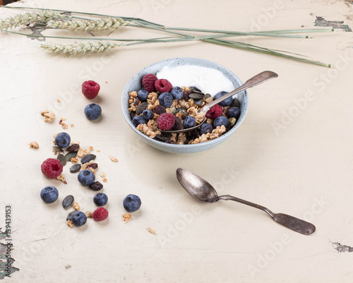 Granola brunch with blueberries and raspberries on rustic wooden table with wheat spiklets. Top View photo