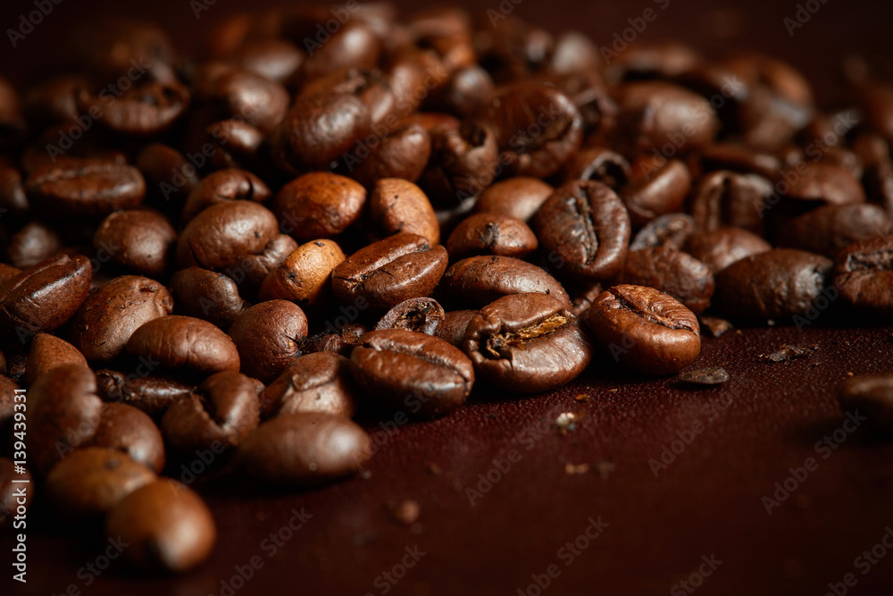 Close up of fresh Roasted coffee beans on brown background Close up of fresh Roasted coffee beans on brown background