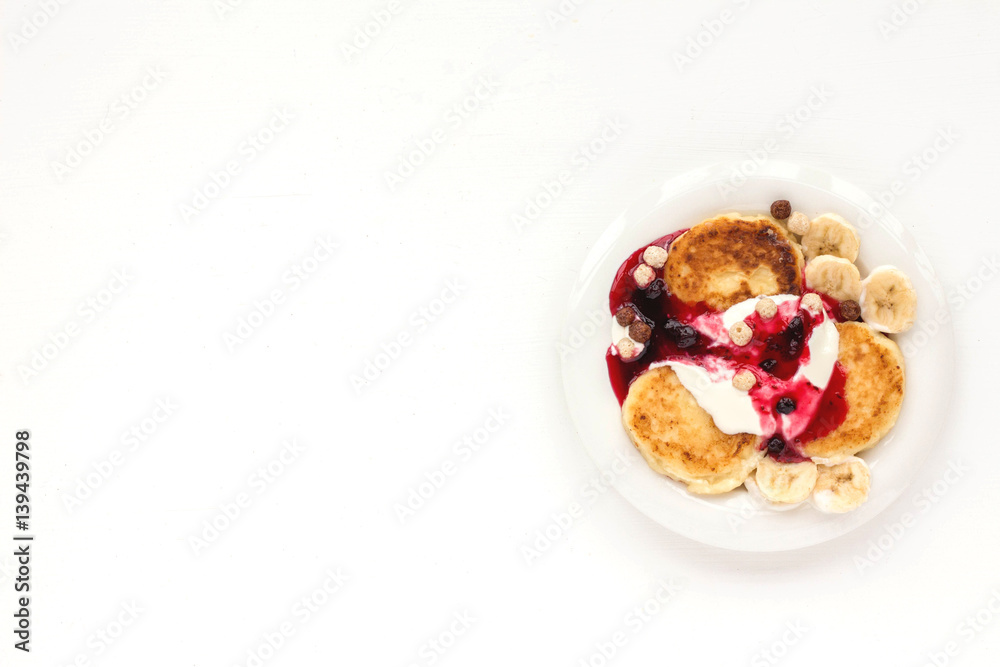 Fototapeta premium Dessert with yogurt, muesli, banana, pancake and berries on white background. Flat lay
