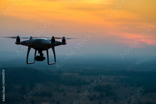 Silhouette of Quad copter flying on a mountain view at beautiful twilight sky.  drone  aerial Vehicle at sundown and copy space.