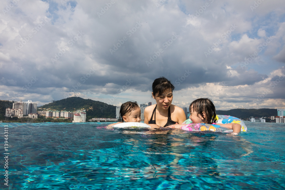 Asian Chinese family playing at the outdoor swimming pool