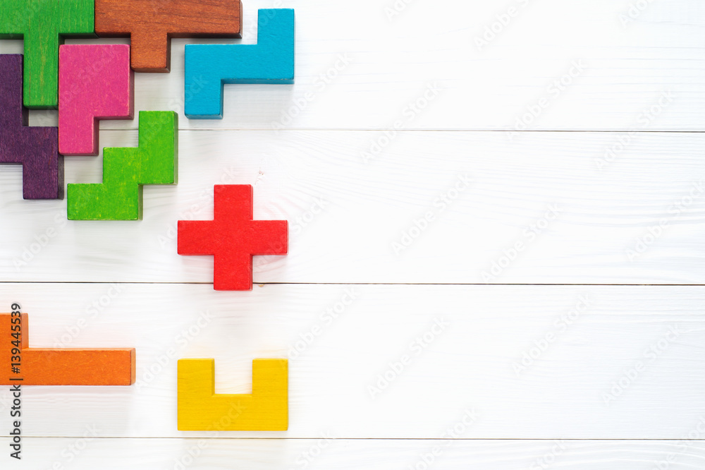 Obraz premium Concept of creative, logical thinking. Different colorful shapes wooden blocks on white wooden background, flat lay, copy space. Geometric shapes in different colors, top view. Abstract Background.