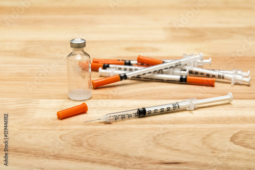 Medical syringe and bottle of potion on wooden desk