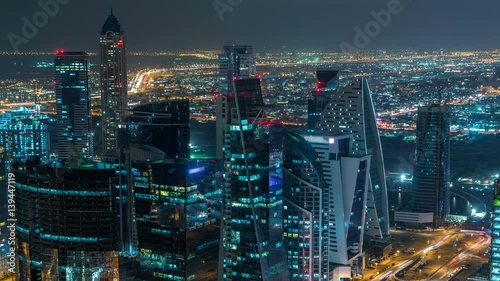 Dubai business bay towers illuminated at night timelapse. Rooftop view of some skyscrapers and new towers under construction. photo