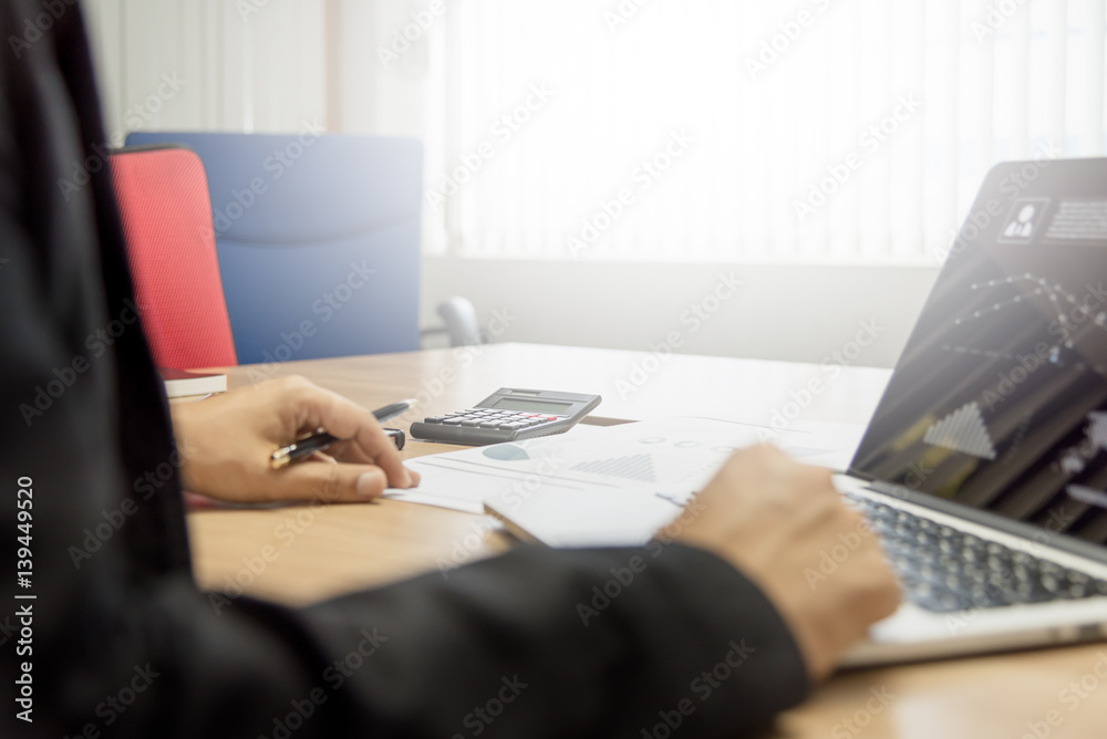 Business man working on his wooden table in the office with calculator,document,smart phone,pen and laptop in business,finance and banking concept Business man working on his wooden table in the office with calculator,document,smart phone,pen and laptop in business,finance and banking concept