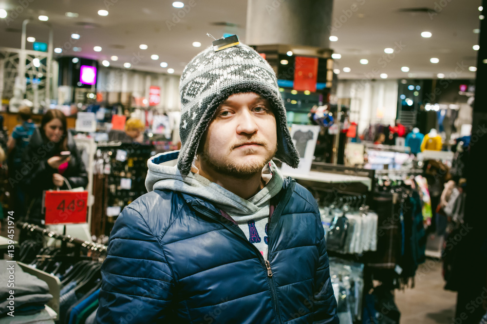 Portrait of a man with a beard with a mustache, putting on winter spring knitted hats in the store, with an emotional face shopping Portrait of a man with a beard with a mustache, putting on winter spring knitted hats in the store, with an emotional face shopping
