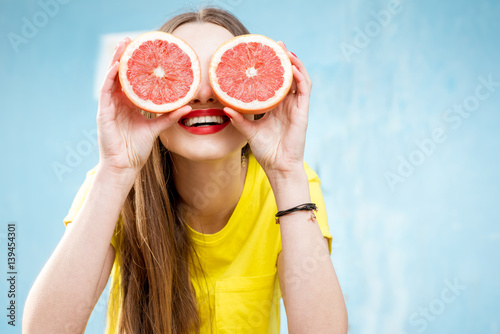 Colorful portrait of a beautiful woman grapefruit slices on the yellow background