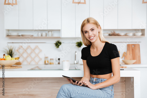 Smiling woman with tablet computer in kitchen