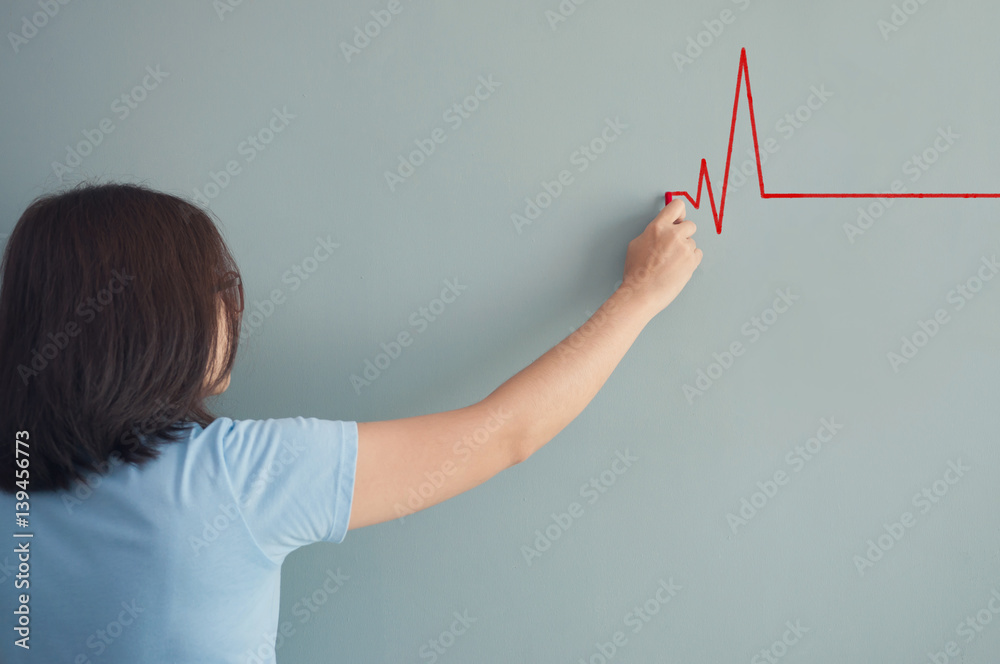 Woman drawing  heartbeat with red chalk on wall.