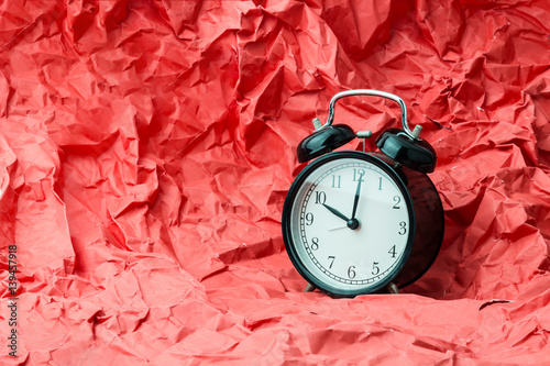 black alrm clock on trash crumpled red paper times concept