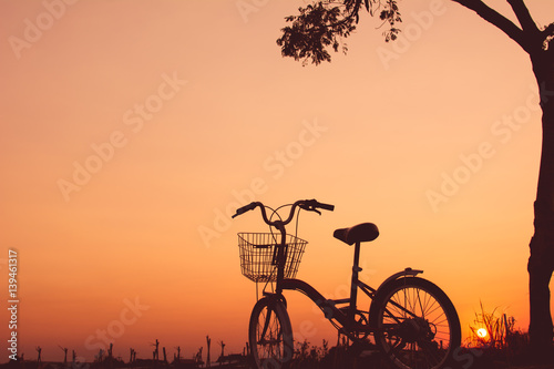 Silhouette of bicycle on grass with the sky sunset © sawitreelyaon