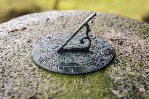 Small metal sundial mounted on a stone plinth