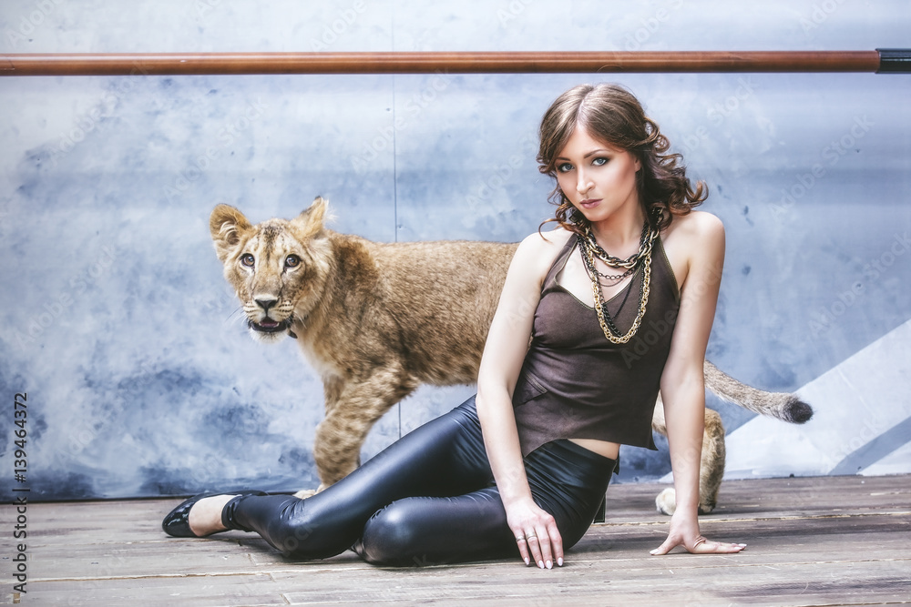 Obraz premium Beautiful fashionable young woman with a little alive lion cub