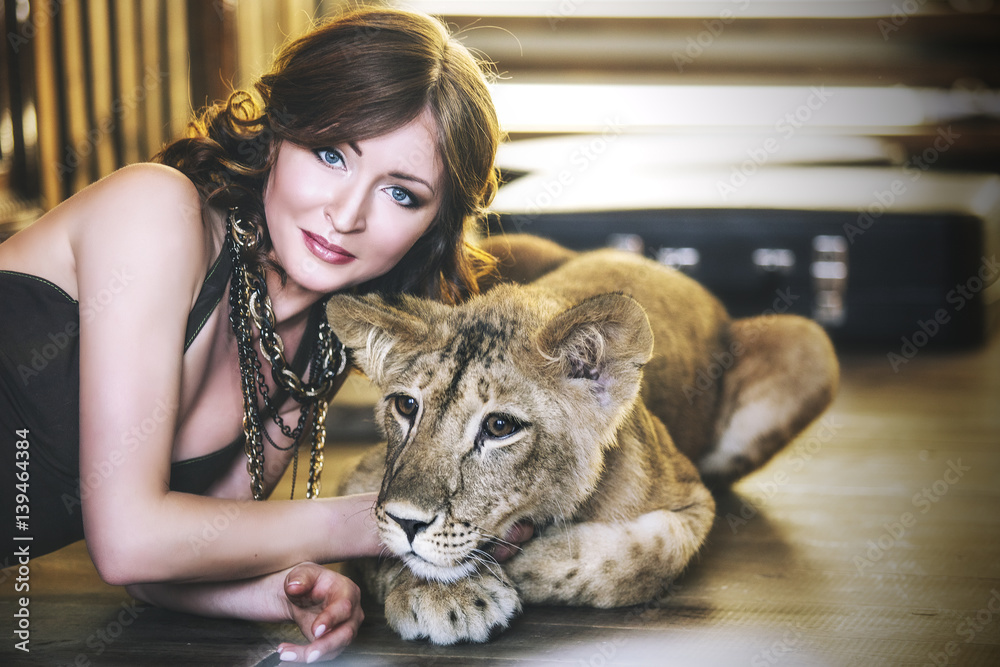 Obraz premium Beautiful fashionable young woman with a little alive lion cub