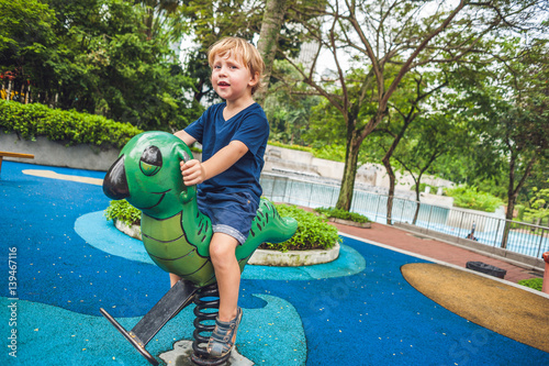 Happy little kid boy playing at colorful playground. Adorable child having fun outdoors photo