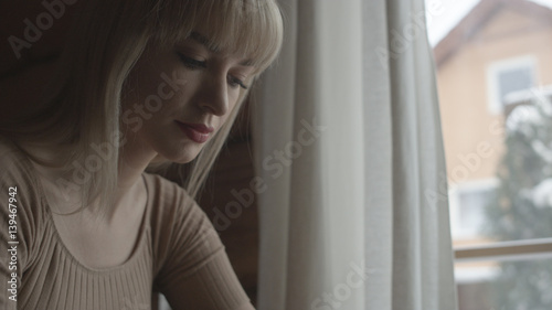 Free Download Young pensive woman sitting on the couch while typing and reading emails on the laptop.  - GFXLoad