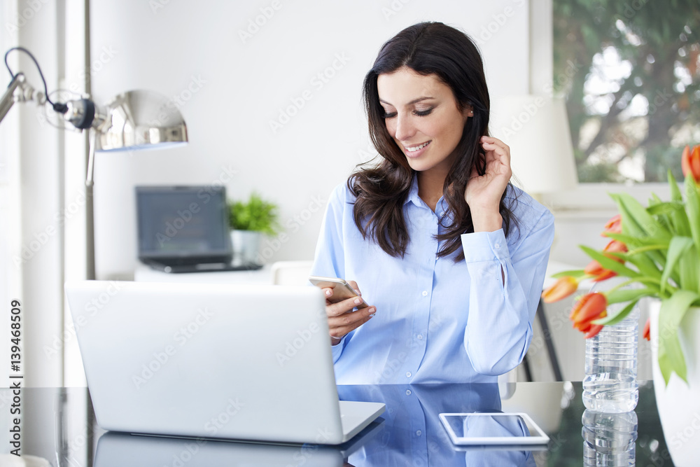Send a message. Portrait of an attractive young businesswoman using her cellphone and text messaging while working in the office. Send a message. Portrait of an attractive young businesswoman using her cellphone and text messaging while working in the office.