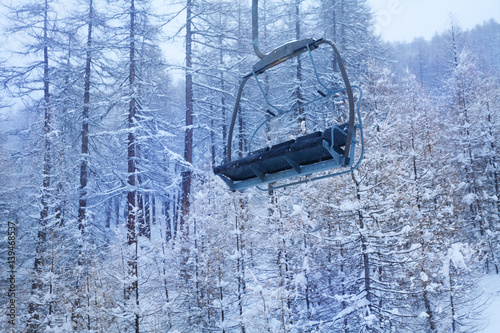 Obraz na płótnie Empty chairlift against snow-covered forest w salonie