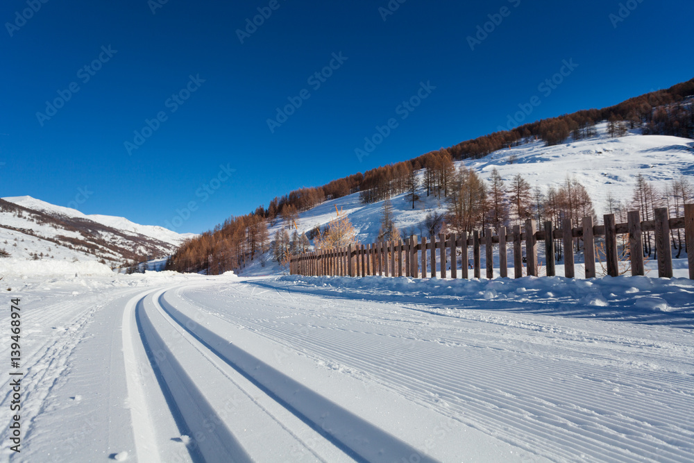 Snowcapped road to alpine resort with ski tracks Snowcapped road to alpine resort with ski tracks
