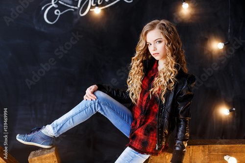 A beautiful blond girl with curly hair in black leather jacket and jeans