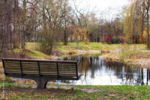 Small pond in the middle of the park with a park bench in front