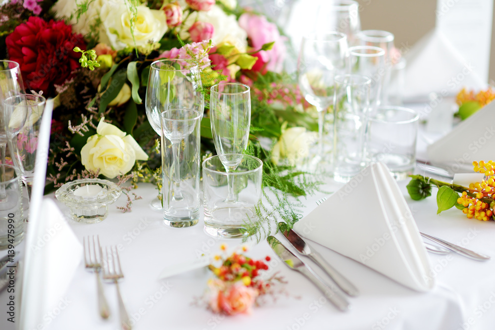 Beautiful table setting with crockery and flowers for a party, wedding reception or other festive event Beautiful table setting with crockery and flowers for a party, wedding reception or other festive event