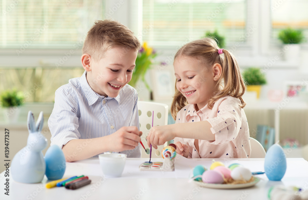 Fototapeta premium Two happy children having fun during painting eggs for easter in spring