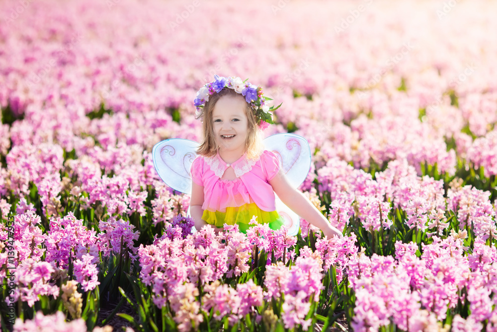Little girl in fairy costume playing in flower field