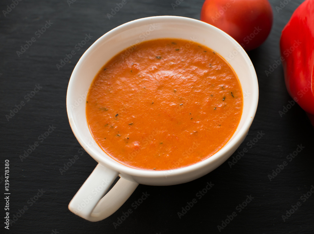 Cream soup with roasted peppers and tomatoes on black plate Cream soup with roasted peppers and tomatoes on black plate