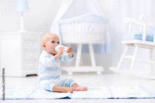 Baby boy drinking milk in sunny nursery