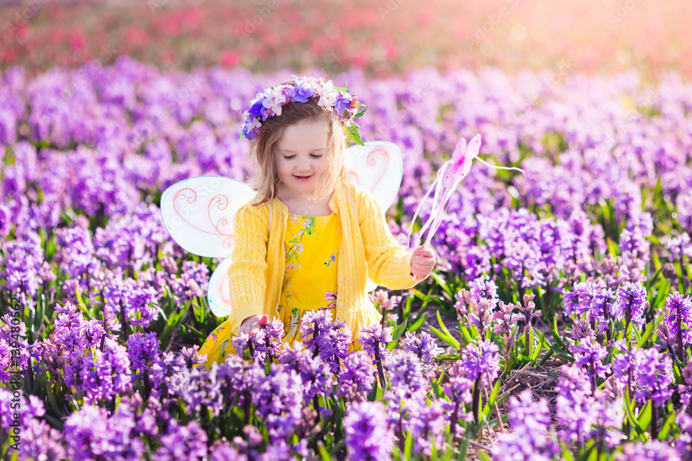 Little girl in fairy costume playing in flower field Little girl in fairy costume playing in flower field