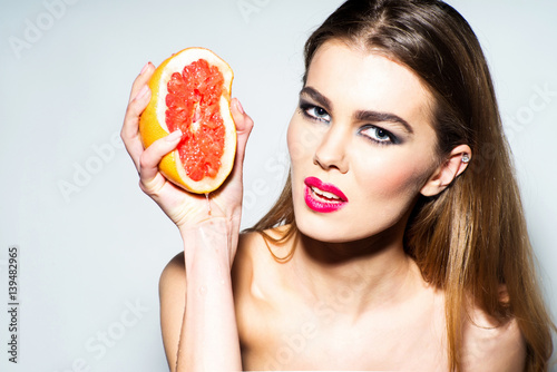 Картината върху платно Pretty girl squeezing juice from fresh orange grapefruit