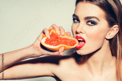 Pretty girl squeezing juice from fresh orange grapefruit