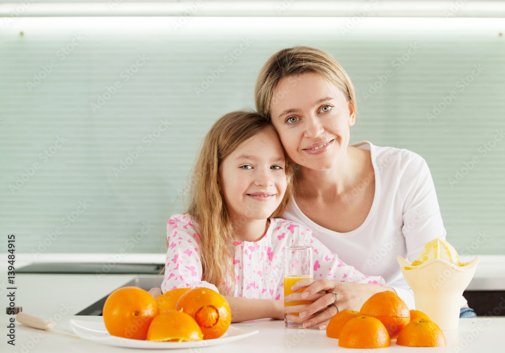 Mother and daughter make orange juice on a juicer
