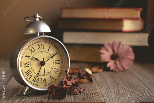 Roman Numeral in Vintage Alarm Clock and Stack of Book Background with Copy Space for Advertise or Web Promote about the Time or Nostalgia Concept