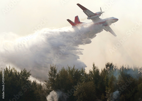 plane drops fire retardant and water on a forest fire photo