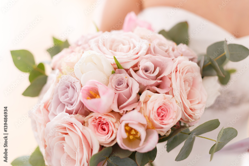 Brides bouquet of roses, tulips and eucalyptus, in her hands