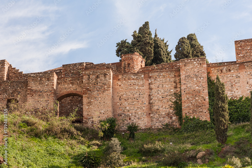 Medieval stone arches, walls and towers of an ancient Alcazaba fortress in Malaga, Spain.