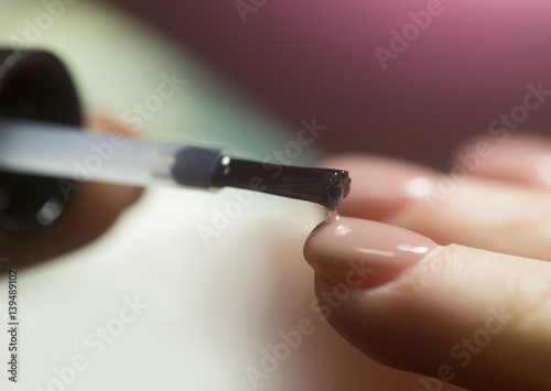 Natural manicure for women's hands in a beauty salon. Brush for manicure and transparent nail polish. Nail care for female beauty. Woman in a nail salon receiving a manicure by a beautician