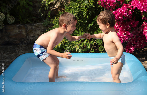 niños jugando en una piscina hinchable en verano photo