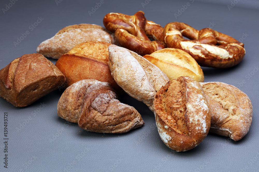 Different kinds of bread and bread rolls on board from above. Kitchen or bakery poster design. Different kinds of bread and bread rolls on board from above. Kitchen or bakery poster design.