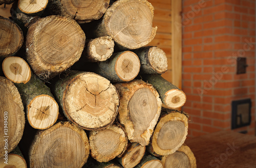 round oak firewood stacked near the stove
