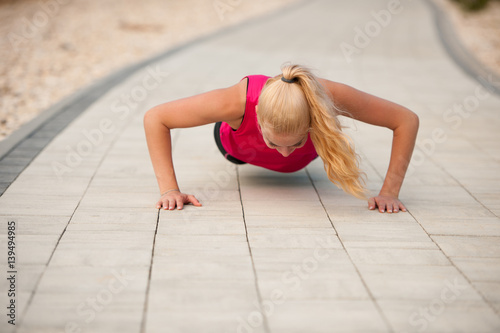 Woman doing pushups on a path near a sea