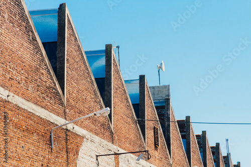 Roof of an old factory with brick wall and lamppost