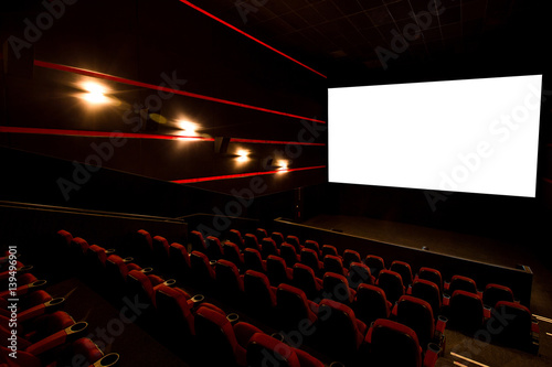 Cinema hall, white screen with copy space and empty armchairs. Movie theatre photo