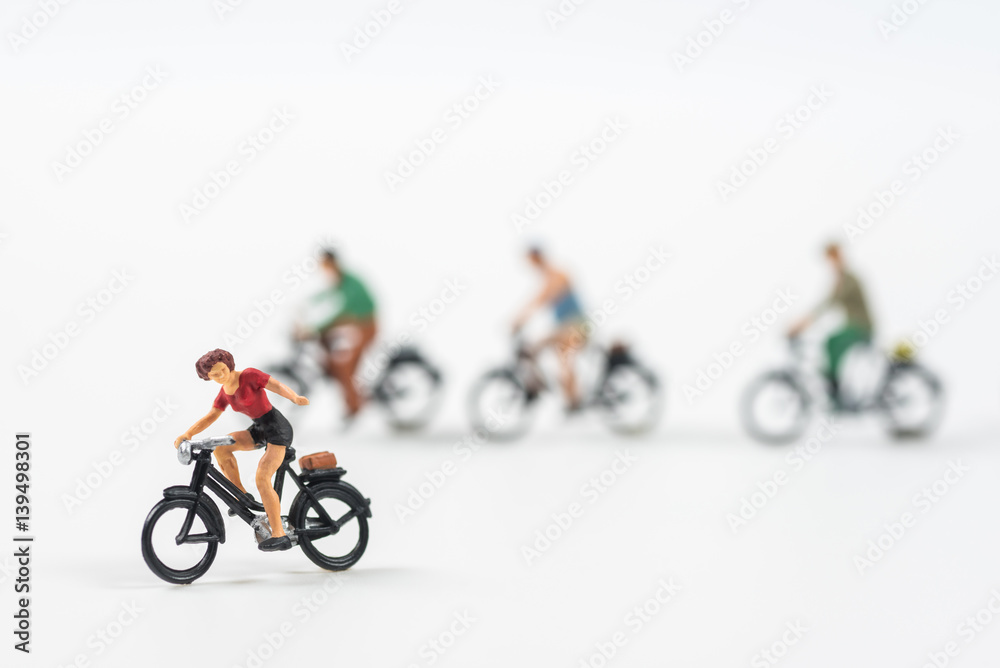 Miniature people cycling on white background