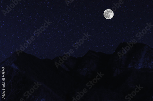 mountain river with stones and grass in the forest at the foot of mountain slope at night in moon light. Azerbaijan