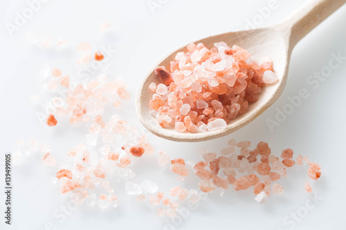 Himalayan salt on a spoon and white table.